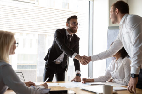 Accountmanager in B2B die de klant een hand geeft om een strategische deal te bezegelen, als symbool voor duurzame groei en marge