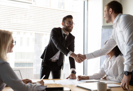 Accountmanager in B2B die de klant een hand geeft om een strategische deal te bezegelen, als symbool voor duurzame groei en marge